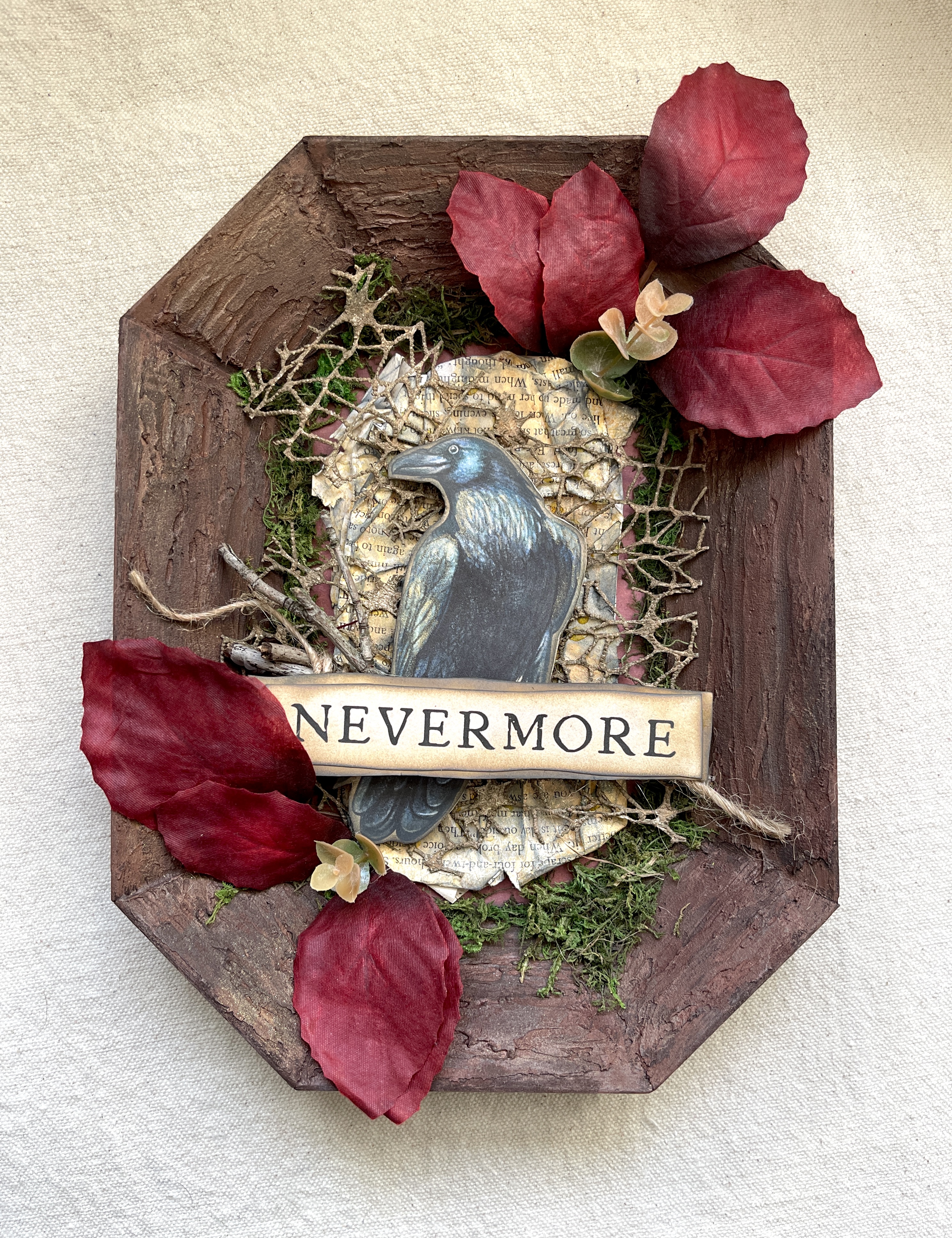 Wood, moss, stick, paper, and textile mixed media art piece with a raven and the word Nevermore